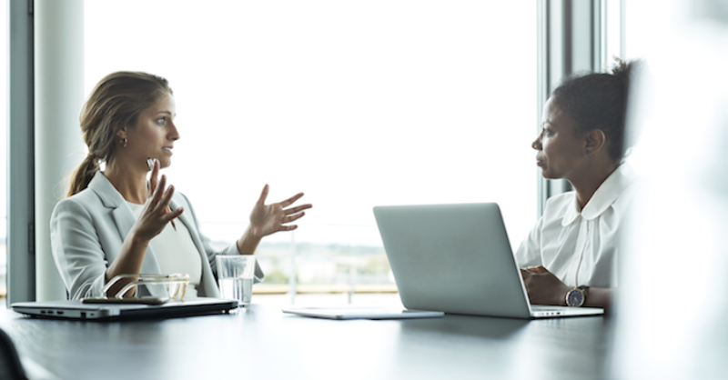 Two people in white dress discussing with each other